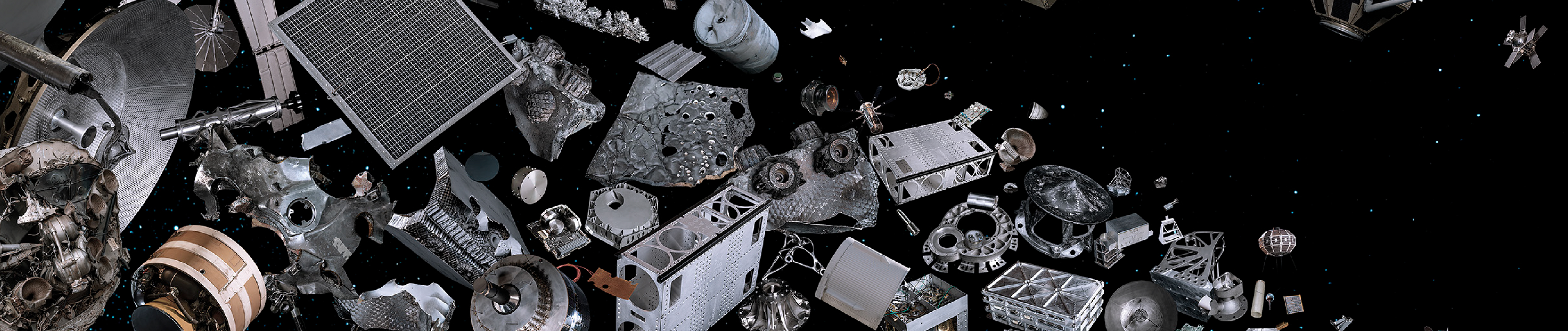 Various grey objects, space junk, are floating in space. Space is black and there are stars twinkling in the distance
